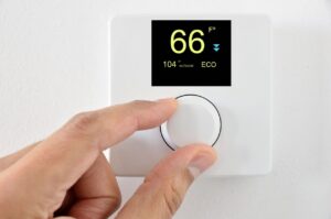person adjusting the temperature on a thermostat